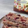 barrette con frutta secca fatte in casa su piatto bianco con bordo scuro accanto a pack dorato bbextra ventura