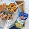 Schiacciate integrali con affettato, formaggio e BBMix Ventura per insalate con Noci, Pistacchi e Mais tostato su un vassoio in legno con piatto e ciotola con cucchiaio in legno e frutta secca