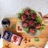mano di donna regge tagliere di legno con cabaret in ceramica pieno di tartufini salati con cranberry, accanto a confezione chiusa di cranberry ventura