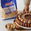 nocciole pelate ventura in busta e in una ciotola e crostata con nocciole con mano di donna che accompagna il piatto