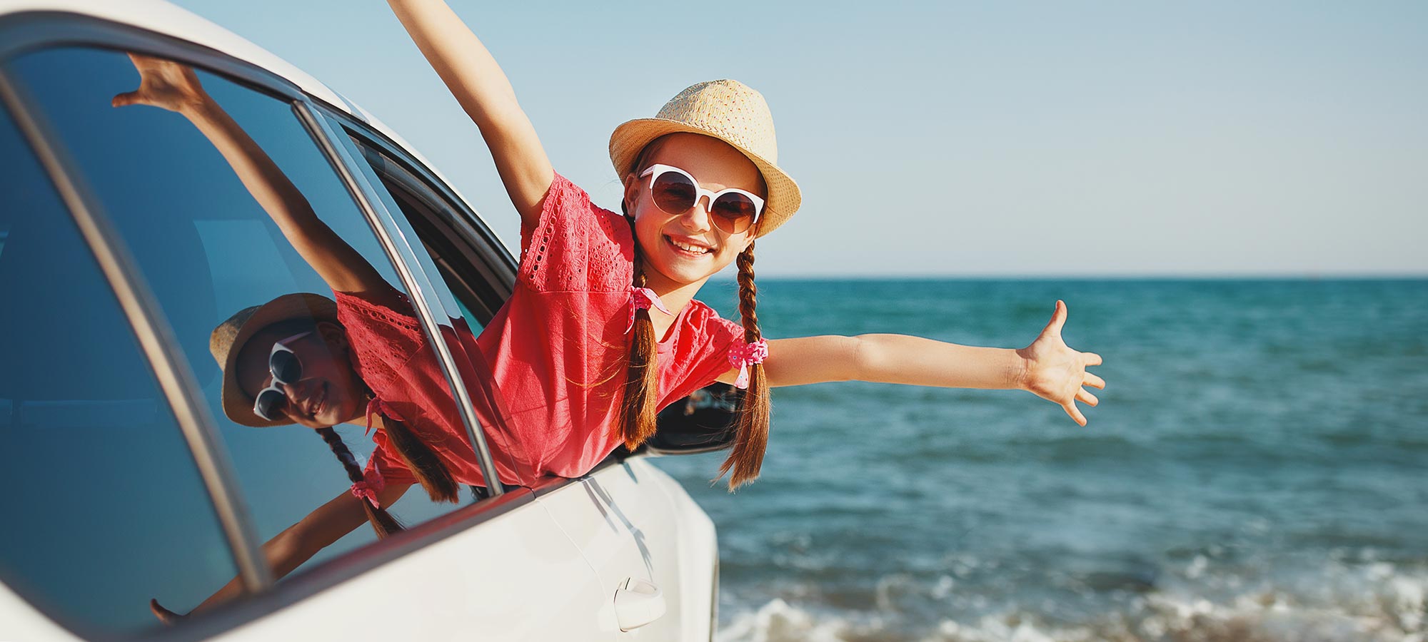 bambina sorridente trecce occhiali da sole si sporge finestrino auto mare