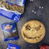 su un tavolo nero, bellissima crostata halloween con faccia di jack skeleton nightmare before christmas accanto a due mele rosse e confezioni di noci e uvetta ventura e qualche paio di simpatici occhi finti adesivi