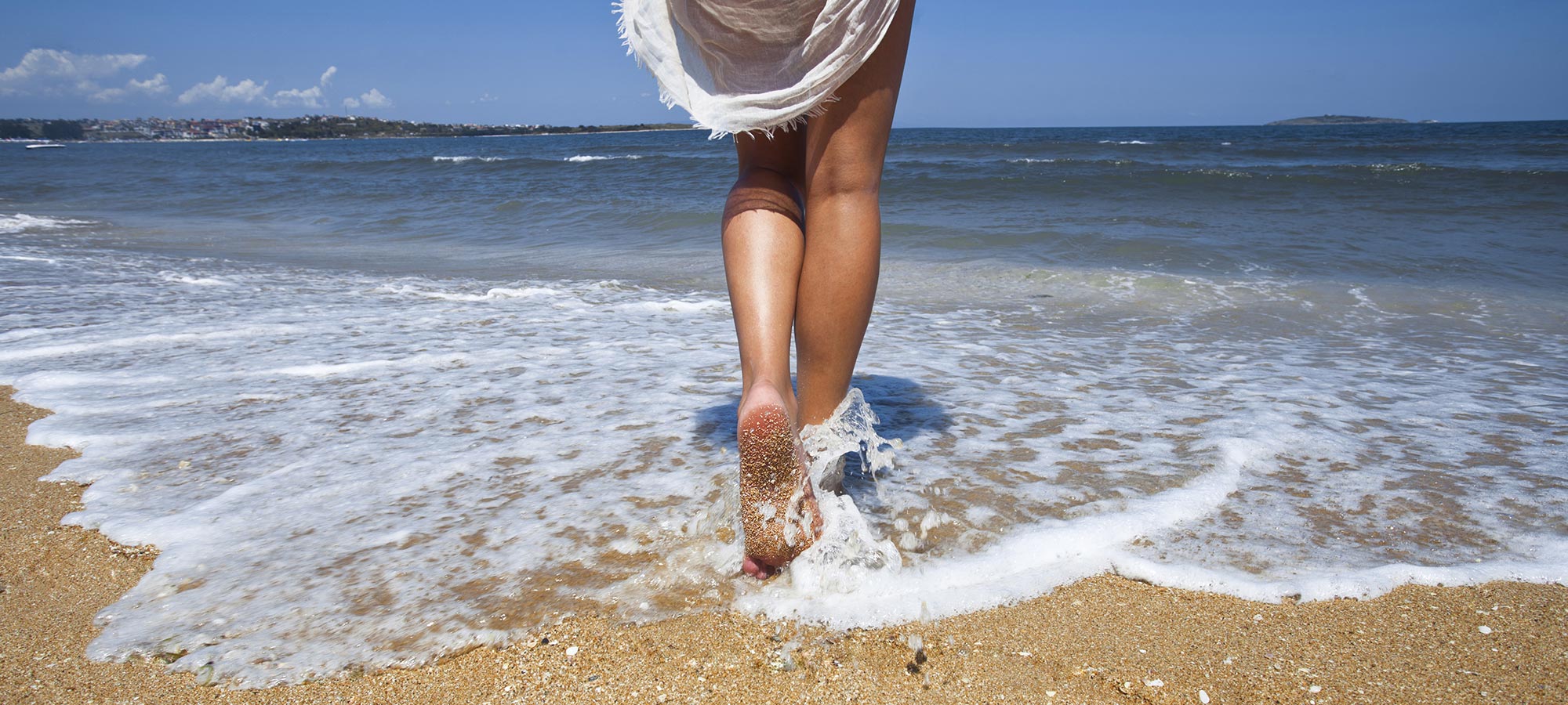 donna camminata in acqua bagnasciuga piedi nudi