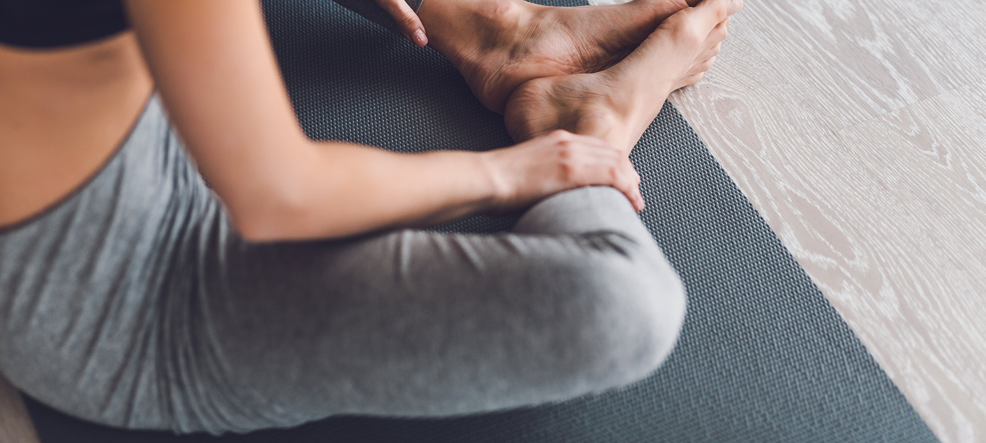 donna seduta a terra tappetino yoga piedi nudi leggins