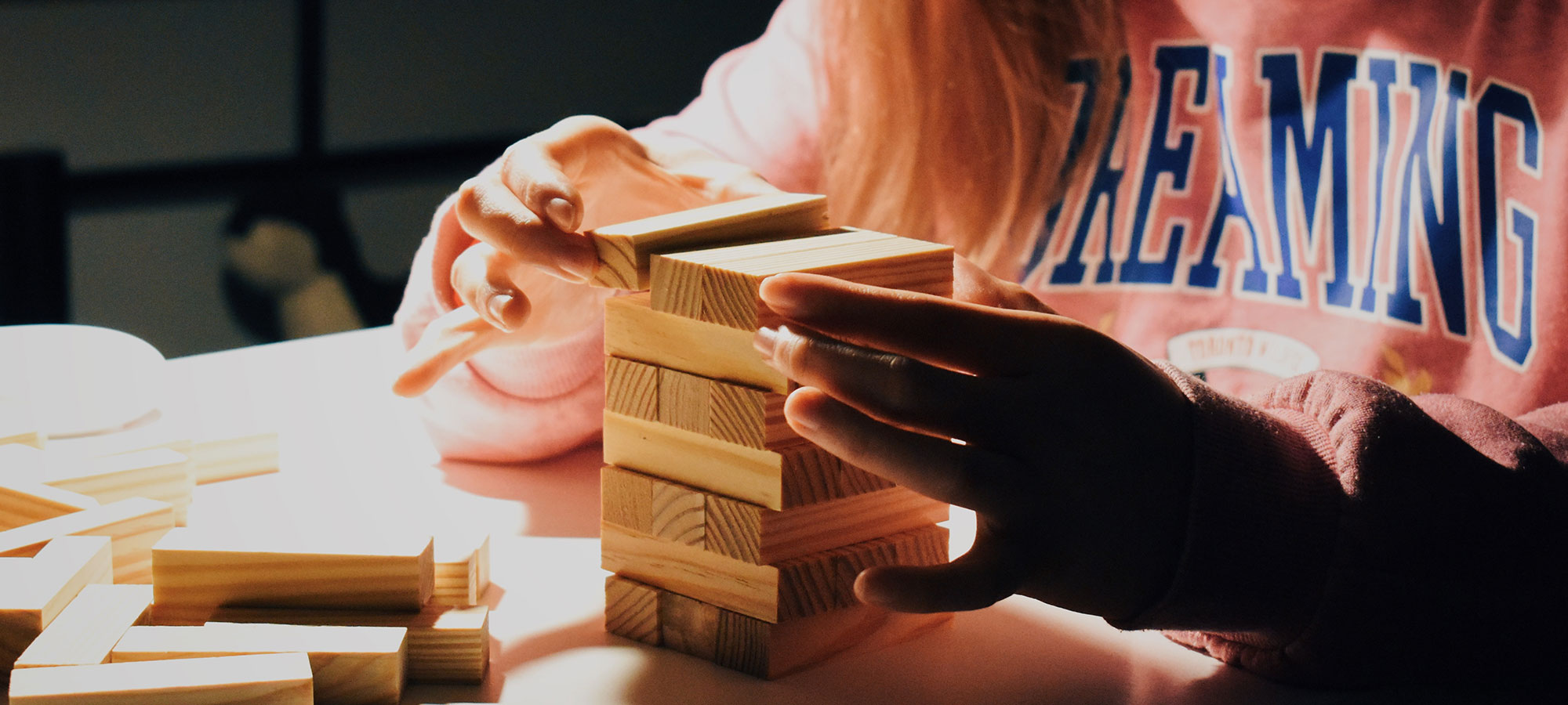 bambina gioca jenga felpa rosa