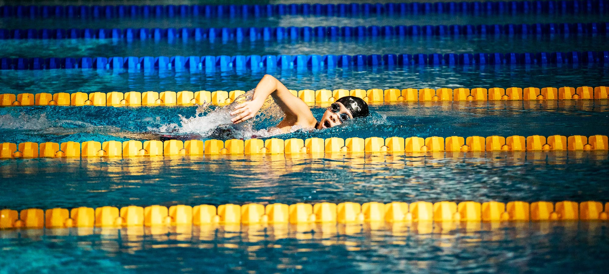 vasca piscina ragazzo nuota cordoni galleggianti gialli e blu