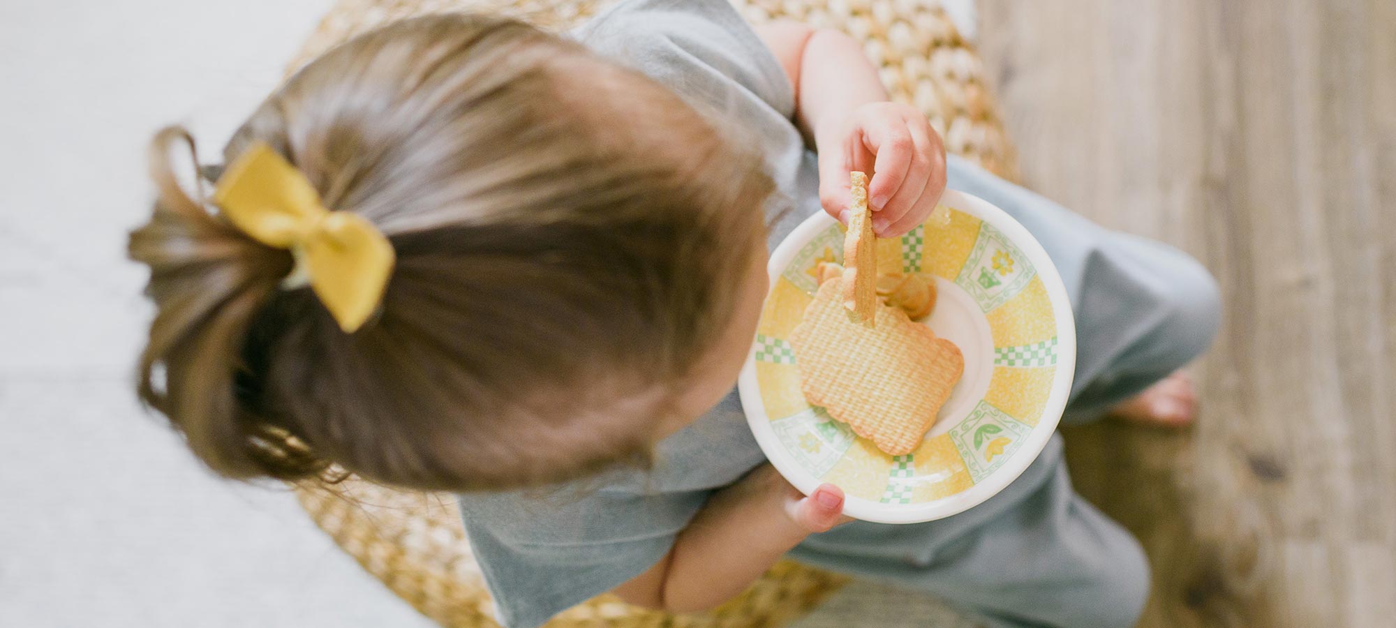 bambina seduta fotografata dall'alto merenda biscotti capelli biondi fiocco giallo