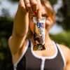giovane donna sportiva con mani curate tiene in mano una confezione di barretta bbextra ventura nocciola e cioccolato