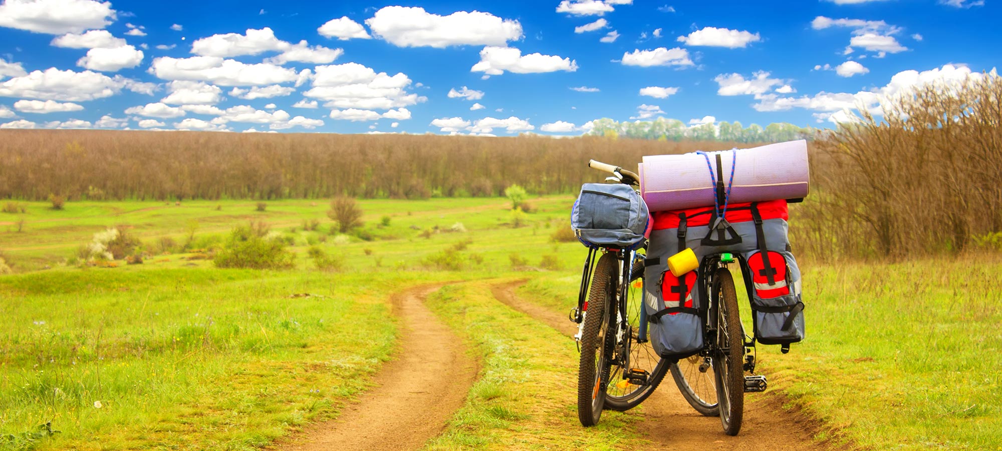 biciclette con bagagli sentiero campagna cielo azzurro con nuvole