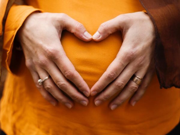 mani di donna su pancia formano un cuore incinta gravidanza