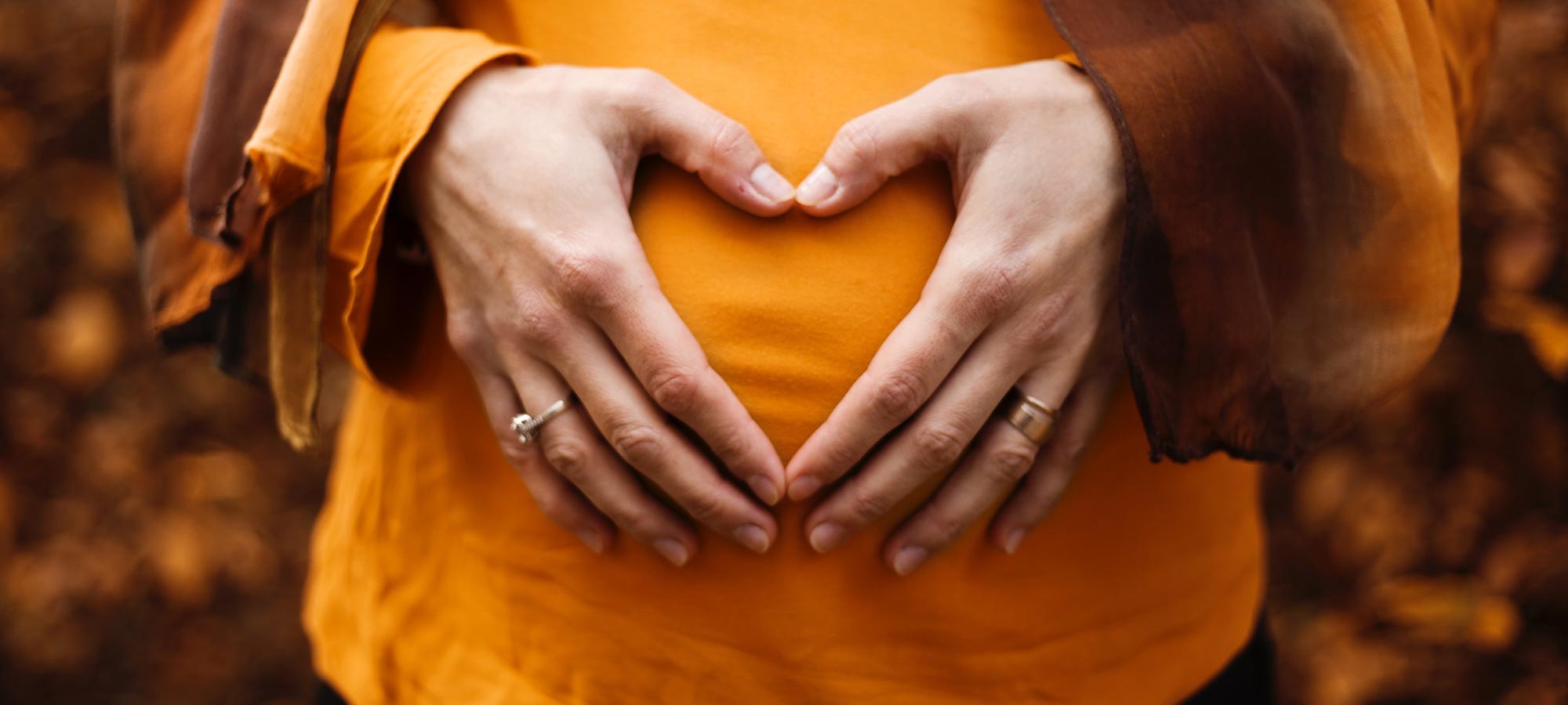 mani di donna su pancia formano un cuore incinta gravidanza