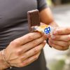 mani di uomo aprono confezione barretta bbextra mandorla ricoperta al cioccolato