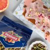 pistacchi sgusciati ventura in busta e in ciotola di ceramica bianca, mezzo pompelmo rosa e plumcake fatto in casa con crema e pistacchi