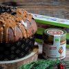 panettone con crema di nocciole e barattolo di crema gourmet ventura con nocciole su tavolo di legno con ramo di abete e bacche rosse